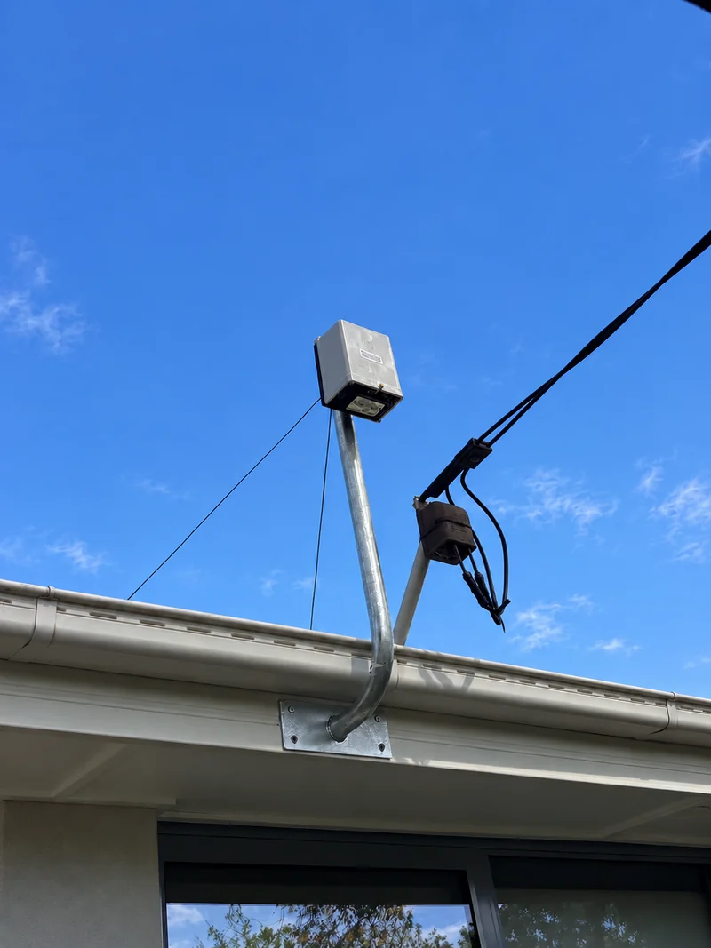 New consumer mains and service bracket installed above the gutter line against a blue sky