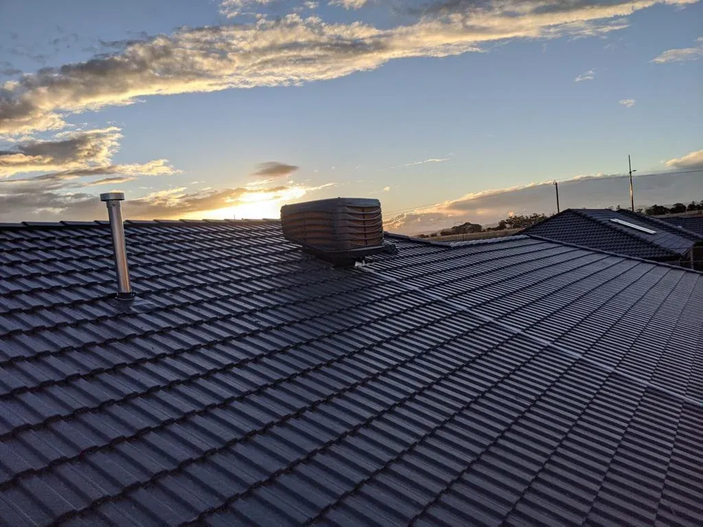 Evaporative cooler on a tiled roof photographed at sunset
