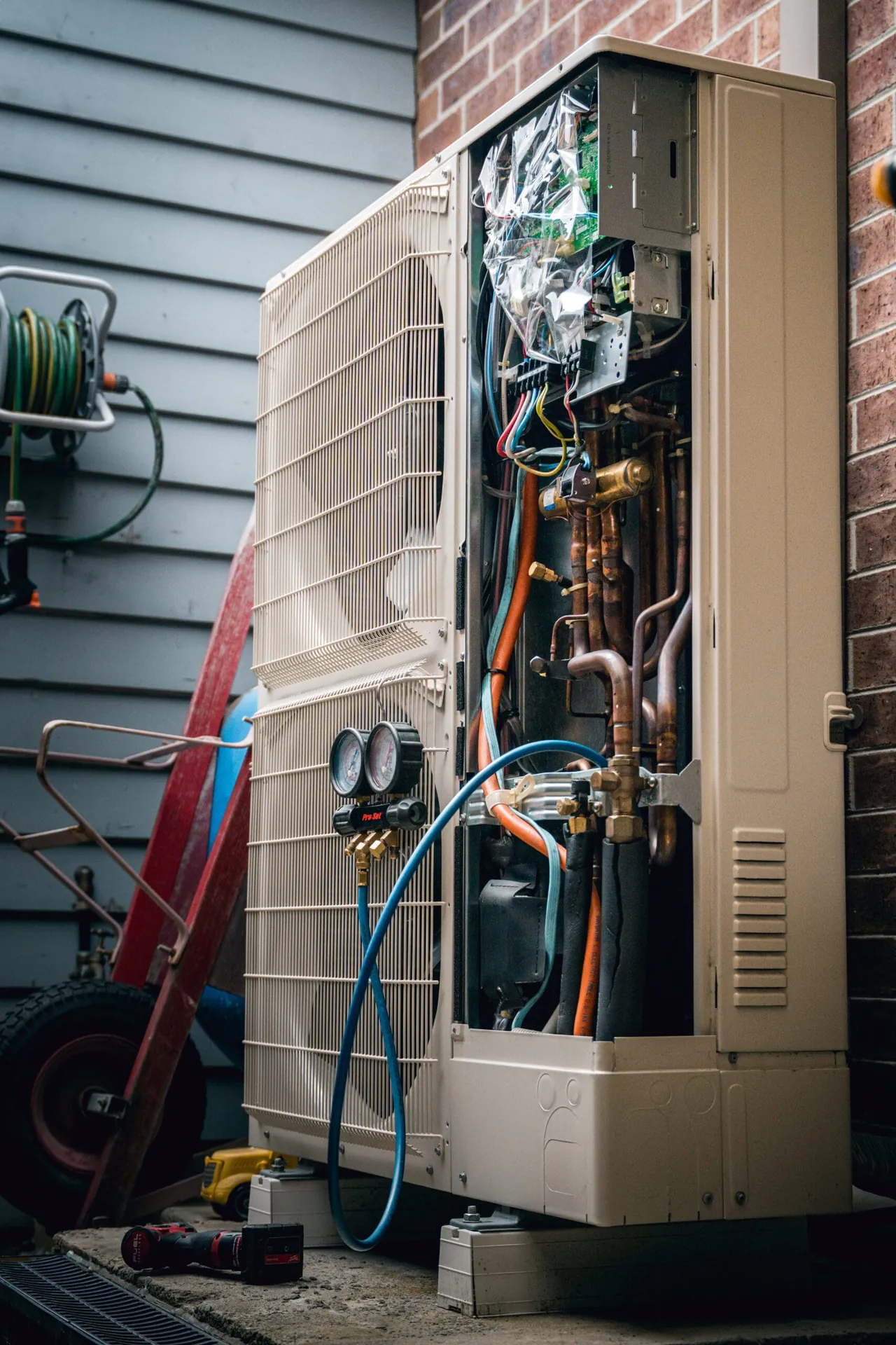 Air conditioning outdoor unit opened up with refrigeration gauges connected during a repair